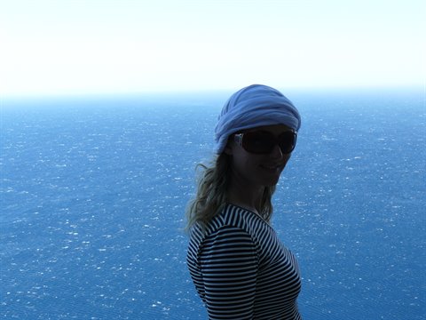 Woman in blue bandana and striped shirt facing the sea