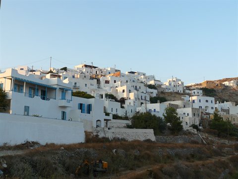 Whitewashed Cycladic village stacked on the hillside in golden light