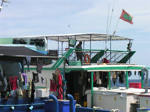 Maldivian dhoni boat with national flag, laundry drying on deck