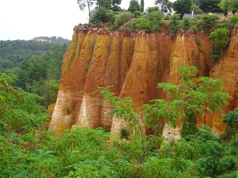 Ochre cliffs at Roussillon, red and yellow rock walls among greenery