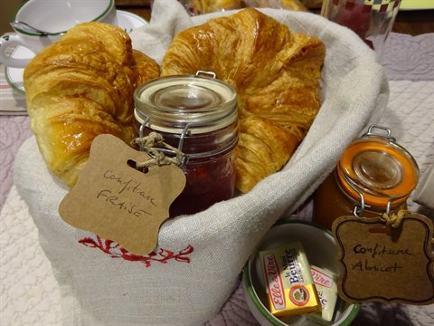 Croissants in a linen basket with jars of homemade jam
