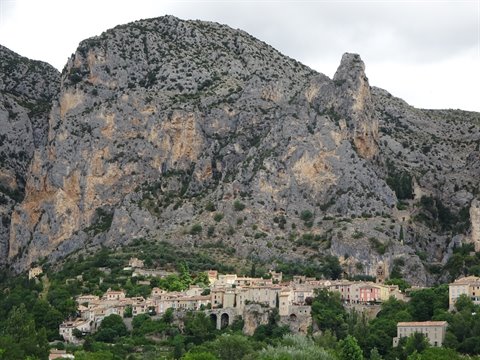 Old stone houses nestled beneath towering limestone cliffs at Moustiers-Sainte-Marie