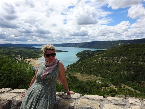 Woman in a green dress leaning on a stone wall above Lake Sainte-Croix