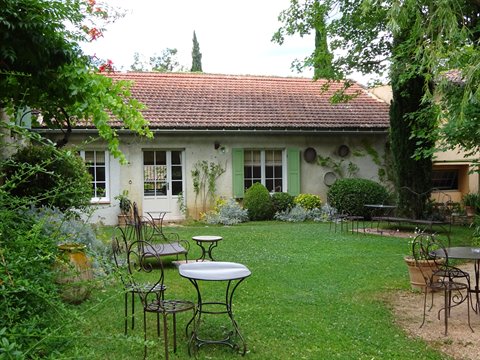 Wrought iron tables on the lawn in front of a house with tile roof