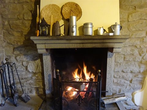 Burning stone fireplace with aluminum pots and straw baskets on the mantel