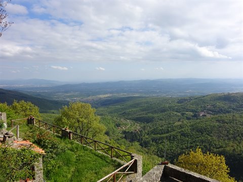 Green wooded hills under white clouds, wooden fence on a stone wall