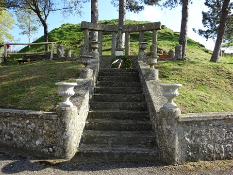 Stone staircase with ornamental urns ascends to monument on grassy mound