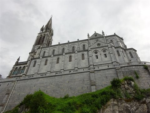 Basilica of the Immaculate Conception in Lourdes, grey stone under cloudy sky