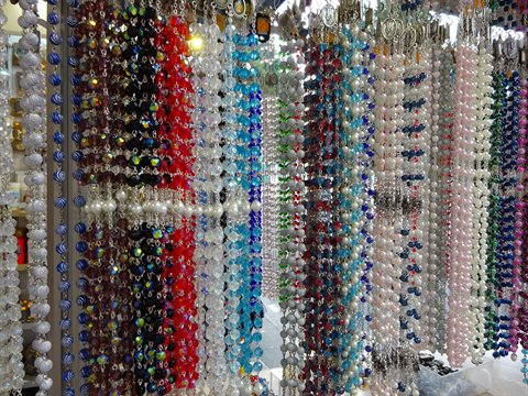 Colorful glass bead rosaries hanging at a souvenir stall