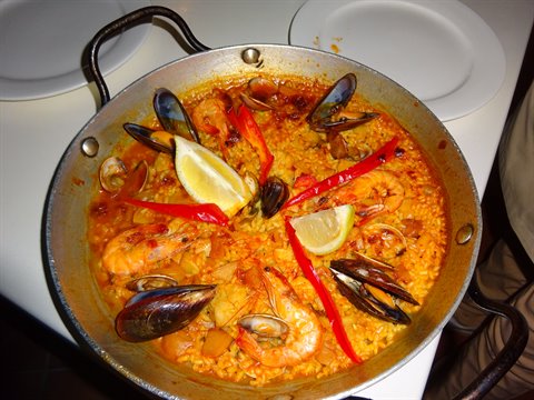 Seafood paella in a steel pan: prawns, mussels, clams, red peppers and lemon
