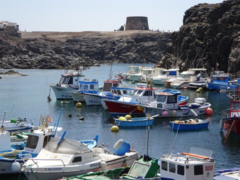 Fishing boats in El Cotillo harbour beneath the old stone tower