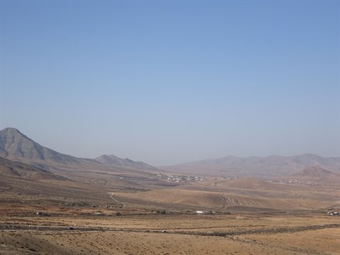 Arid mountains and a white village in the valley under blue sky
