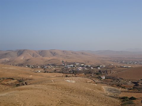 White village among dry brown hills under blue sky, Fuerteventura
