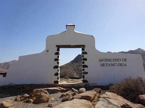 Whitewashed archway reading Municipio de Betancuria framed by volcanic mountains under blue sky