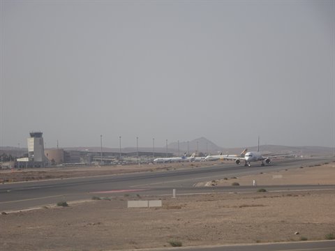 Airplane taxiing on Sharm el-Sheikh airport runway, desert and hazy sky