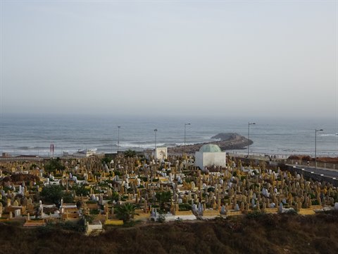 Cimitero con tombe bianche e cupola verde davanti all'oceano, Rabat