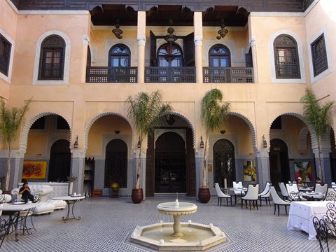 Cortile di riad a Fes con fontana, palme e archi, luce morbida