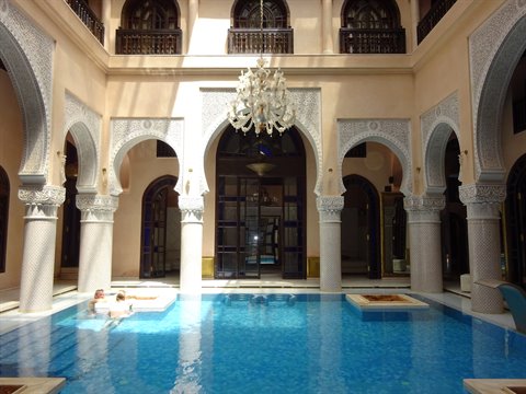 Piscina interna tra archi scolpiti e lampadario a cristallo, riad di Fes