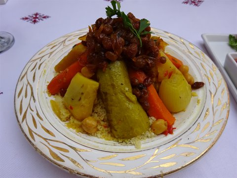 Couscous con verdure, cipolla caramellata e uvetta su piatto dorato