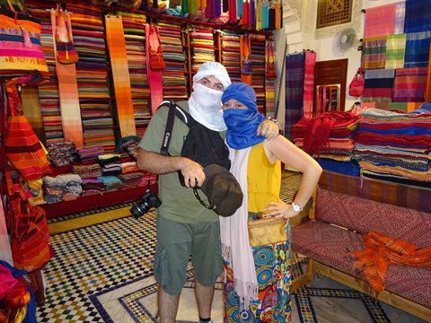 Turisti con kefiah e maiolica in un negozio di tessuti, Fes
