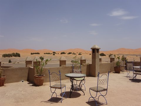 Tavolo in ferro battuto sulla terrazza, dune di Merzouga sullo sfondo