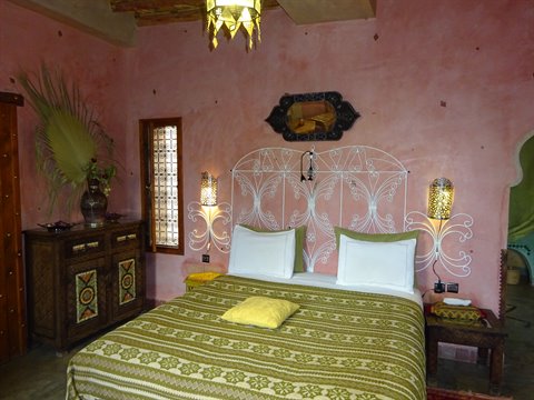 Camera con letto in ferro battuto, pareti rosa e lampade marocchine accese