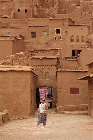 Turista cammina tra le case di terra dell'antico ksar di Ait Ben Haddou