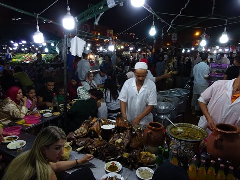 Cook in white cap serving roasted meat at Jemaa el-Fna night market, Marrakech