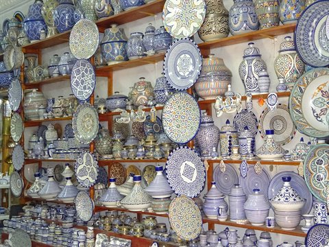 Blue and white ceramic plates and tajines displayed on shop shelves, Fes