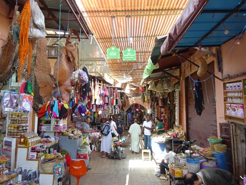 Covered souk in Marrakech, spice stalls and colorful baskets under reed roof