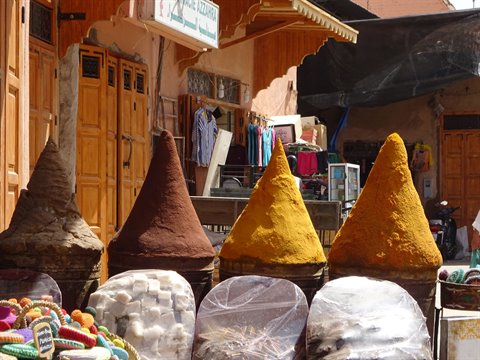 Coni di spezie gialle e marroni davanti alle bancarelle della medina di Marrakech