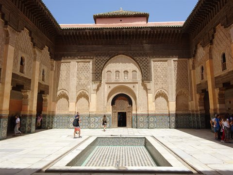 Medersa Ben Youssef, cortile in marmo con fontana e intarsi, visitatori sotto il sole