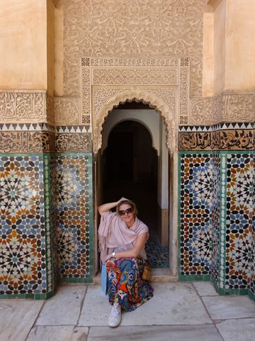 Donna sorridente accanto a porta ad arco con zellige a Fes