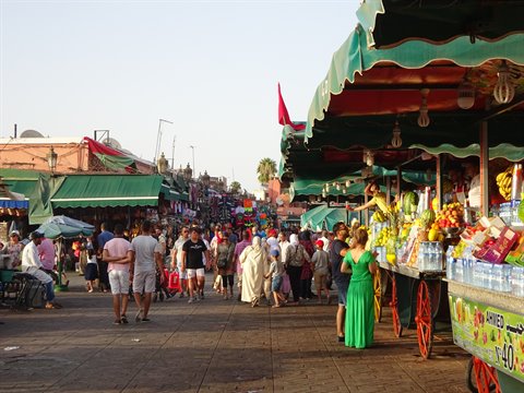 Fruit carts under green awnings in the crowded Jemaa el-Fna square, Marrakech