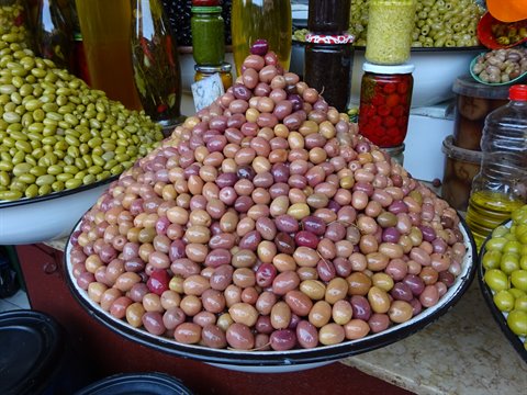 Pyramid of purple and green olives in metal basin at Fes market
