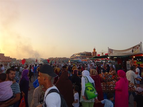 Crowd among food stalls at Jemaa el-Fna, Marrakech, golden light and smoke