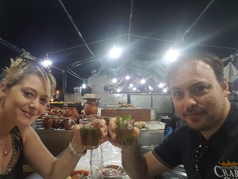 Couple toasting mint tea under the lights of a night food market