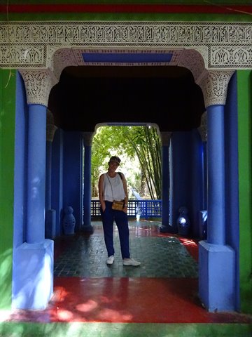 Tourist under carved archway at Jardin Majorelle, blue columns, Marrakech