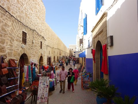 Tourists walk past leather stalls in Essaouira's whitewashed medina