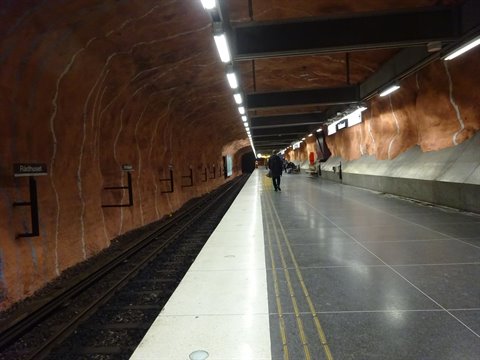 Tourist on Rådhuset metro station platform, red bedrock cave in Stockholm