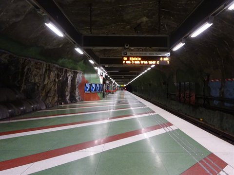 Empty platform in a rock-carved metro station, neon lights