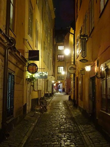 Night cobblestone alley in Gamla Stan, Stockholm, lamps glowing on walls