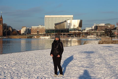 Woman posing on snow in front of the Waterfront Building and Stockholm City Hall