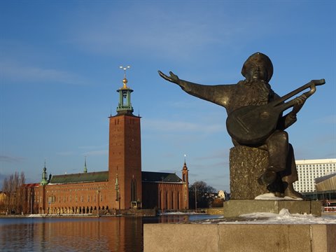 Evert Taube bronze statue with lute before Stockholm City Hall by the water