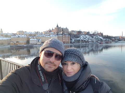 Winter couple selfie in front of snowy Södermalm buildings, Stockholm