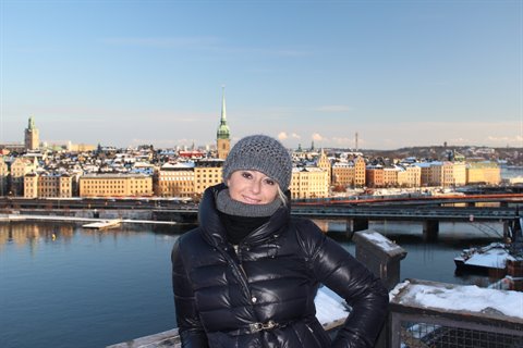 Woman in black coat in front of Gamla Stan colorful buildings, Stockholm
