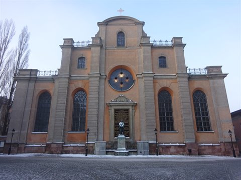 Ochre facade of Storkyrkan in Stockholm with rose window, snow on ground