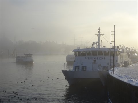 The ferry Vindhem moored at the snowy quay, fog over Stockholm harbor
