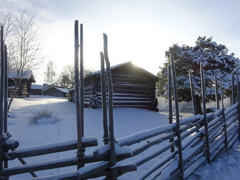 Snow-covered log cabins and wooden fence in Stockholm