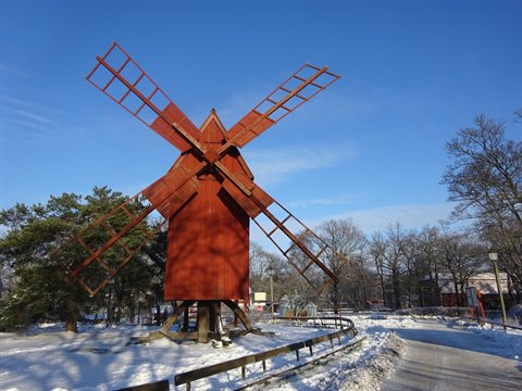 Red wooden windmill at Skansen, Stockholm, surrounded by snow and bare trees